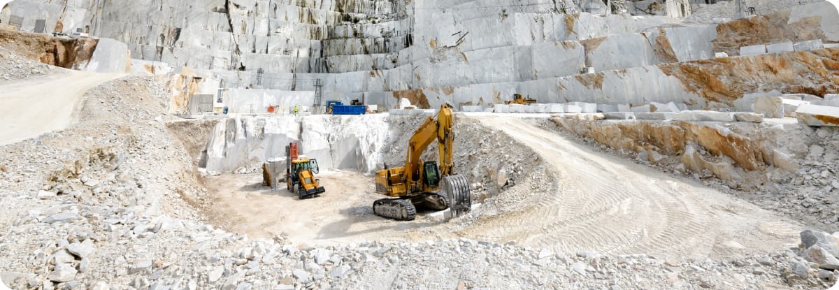 Equipamentos de minera&ccedil;&atilde;o operando em uma pedreira, representando a ind&uacute;stria extrativa.